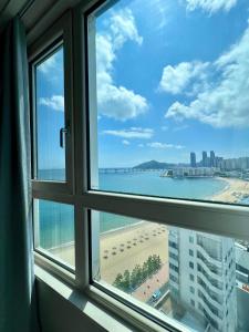 una ventana con vistas a la playa y al océano en Entire Studio Apartment - Busan Gwangalli Beachfront Bliss 광안리 드림홈, en Busan