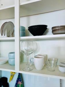 Un armario lleno de platos y tazas y una copa de vino. en Entire Studio Apartment - Busan Gwangalli Beachfront Bliss 광안리 드림홈, en Busan