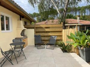 a patio with chairs and a table and a fence at Entre bourg et plage, climatisé, grande terrasse, WIFI, parking gratuit, linge et ménage compris in Mimizan