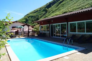 a swimming pool in front of a house with a mountain at Les Sources de La Nive in Esterençuby