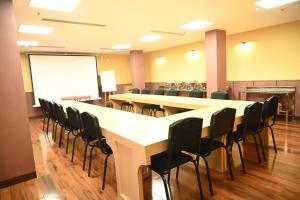 Una sala de conferencias con mesas, sillas y una pizarra. en Hotel Shaktiheritage Inn, en Bhubaneshwar