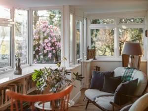 sala de estar con ventanas, sofá y silla en Strathcashel Cottage, en Rowardennan