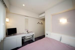 um quarto com uma cama, uma secretária e uma televisão em Hotel Mid In Meguro Ekimae em Tóquio