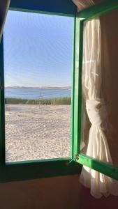a window view of a beach with a wedding dress at Marcelia Eco-Village Front Lake View in Siwa