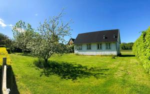 ein weißes Haus mit einem schwarzen Dach und einem Baum in der Unterkunft Cottage With Views Over Nature Reserve In Arild in Arild