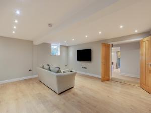 a living room with a couch and a flat screen tv at Clarion Lodge Cottage Ilkley in Menston