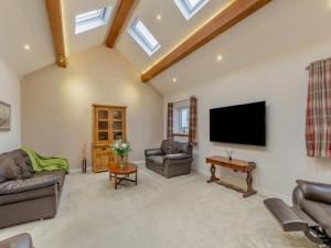 a living room with couches and a flat screen tv at Clarion Lodge Cottage Ilkley in Menston