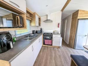 une cuisine avec des appareils électroménagers blancs et des armoires en bois dans l'établissement Beautiful 6 Berth Caravan With Decking In Norfolk Ref 89001Mv, à Belton