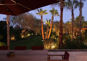 a patio with palm trees and a table and chairs at Vyylla Private Resort in Saint-Tropez