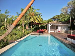 a swimming pool in a backyard with palm trees at Vyylla Private Resort in Saint-Tropez