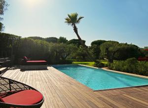a swimming pool with two chairs and a palm tree at Vyylla Private Resort in Saint-Tropez