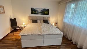a white bed in a room with a window at Modern apartment Pilatus view self check-in in Stans