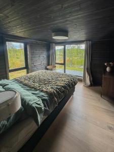 ein Schlafzimmer mit einem großen Bett in einem Zimmer mit Fenstern in der Unterkunft Mountain Cabin With Beautiful Lake View in Markegardlian