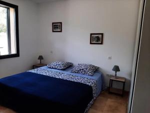 a bedroom with a blue bed with two pillows at Villa 2 chambres - Piscine et spa in Mignataja