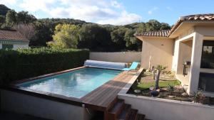a swimming pool with a wooden deck next to a house at Villa 2 chambres - Piscine et spa in Mignataja +10 photos