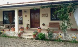 a house with a porch with potted plants and a bench at B&B RoLu in Prima Porta