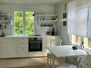 une cuisine avec des armoires blanches, une table et une fenêtre dans l'établissement Traditional Cottage Near Linné's Råshult, à Stenbrohult