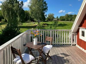 une table et des chaises sur une terrasse avec un vase de fleurs dans l'établissement Traditional Cottage Near Linné's Råshult, à Stenbrohult