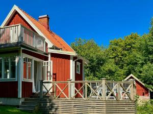 une maison rouge avec une terrasse couverte et une terrasse dans l'établissement Traditional Cottage Near Linné's Råshult, à Stenbrohult