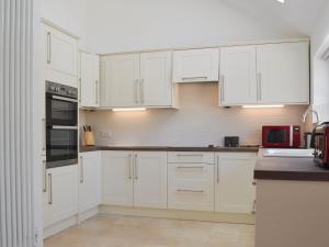 a white kitchen with white cabinets and appliances at The Hop Cottage in Ashperton