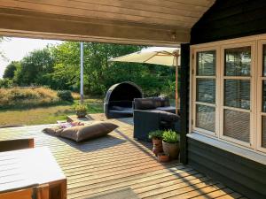 eine Holzterrasse mit einem Stuhl und einem Sonnenschirm in der Unterkunft Holiday Home By Viking Grave And Protected Nature in Korsør