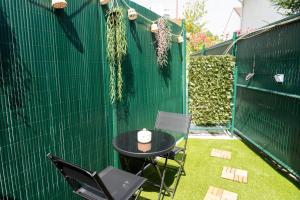 a patio with a table and chairs and a green wall at Douceur de Soie - Private Spa in Fresnes