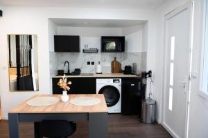 a kitchen with a table and a washing machine at Douceur de Soie - Private Spa in Fresnes