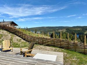 a wooden deck with two chairs and a bridge at Architect-Designed Cabin With Lake Mylla Views in Roa