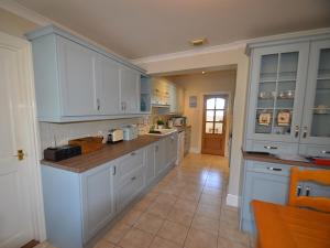 a large kitchen with white cabinets and a tile floor at Riverview in Fowey
