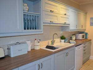 a kitchen with white cabinets and a sink at Riverview in Fowey +9 photos