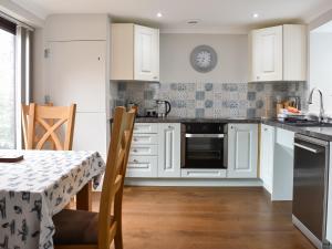 a kitchen with white cabinets and a table at The Martins - Uk47429 in Bewaldeth