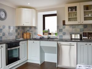 a kitchen with white cabinets and black appliances at The Martins - Uk47429 in Bewaldeth