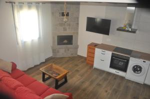 a living room with a red couch and a fireplace at Casa rural La Zarzosa in La Serrada