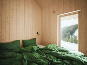 a bedroom with a bed with green sheets and a window at Architect-Designed Cabin With Lake Mylla Views in Roa
