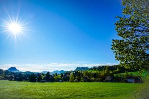 a green field with the sun in the sky at Kaiser`s Holiday Home Apartments mit privater Sauna in Struppen