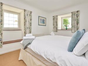 una camera da letto con un grande letto bianco e due finestre di Holly Cottage - 28140 a Boreland of Colvend