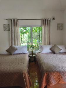two beds in a room with a window at Melany's House's in Ajaxá +25 photos