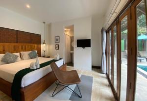 a bedroom with a bed and a chair and a television at Baan Khao Hua Jook in Chaweng