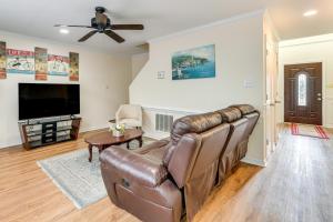 a living room with a leather couch and a flat screen tv at Classic Colonial Home with Private Yard in Richmond! in Beulah Village