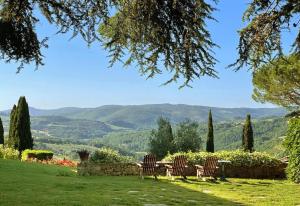 Un grupo de sillas colocadas en un césped con montañas al fondo. en Villa Cavresa, en Fattoria Montecchio