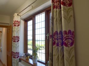 ein Zimmer mit einem Fenster mit Vorhängen und einer Pflanze in der Unterkunft Railway Cottage in Brassington