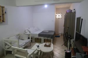 a room with two beds and a table and a tv at Nyumbani Studio in Ukunda Airport