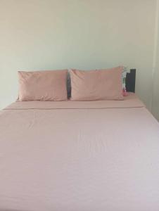 a white bed with two pink pillows on it at Bulls residence seaview in Toledo City
