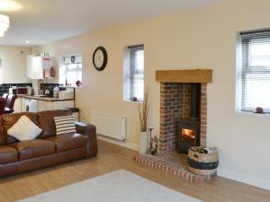 ein Wohnzimmer mit Couch und Kamin in der Unterkunft Abbey Cottage in Longhirst