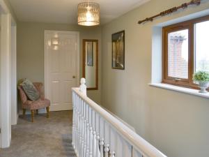 einen Flur mit einer Treppe mit einem Stuhl und einem Fenster in der Unterkunft Carp Cottage - Ukc1907 in Doddington