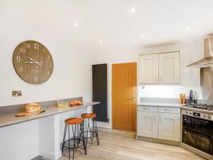 a kitchen with white cabinets and a clock on the wall at Gwel Y Castell - Uk48828 in Harlech