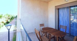 マラケシュにあるAppartement à Marrakech Terrasse et piscineのバルコニー(木製のテーブルと椅子、窓付)