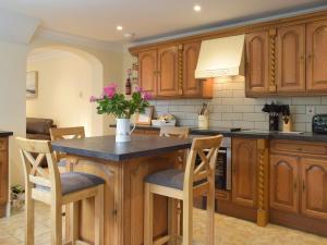 a kitchen with wooden cabinets and a table with chairs at Victoria House - Uk13380 in Llanstephan