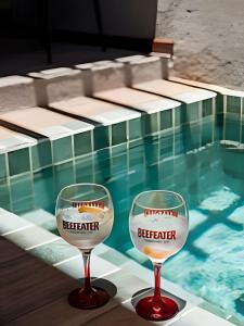 zwei Weingläser neben einem Pool in der Unterkunft Aconchego de Milagres Casa2 750m praia do Riacho. in São Miguel dos Milagres