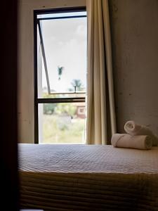 ein Schlafzimmer mit einem Bett mit Fenster und Handtüchern in der Unterkunft Aconchego de Milagres Casa2 750m praia do Riacho. in São Miguel dos Milagres